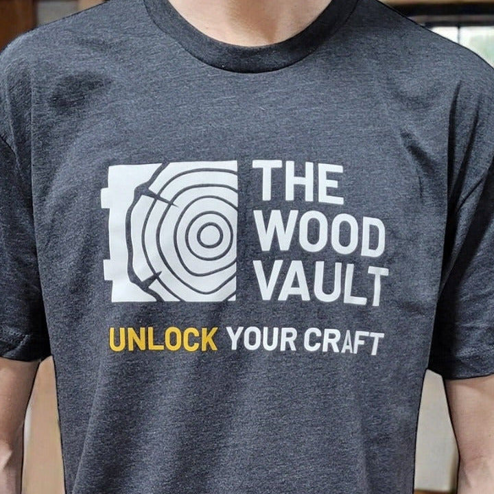 Person wearing a t-shirt with 'The Wood Vault' logo in a workshop setting