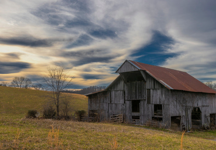 Old wooden barn in a field with a dramatic sky