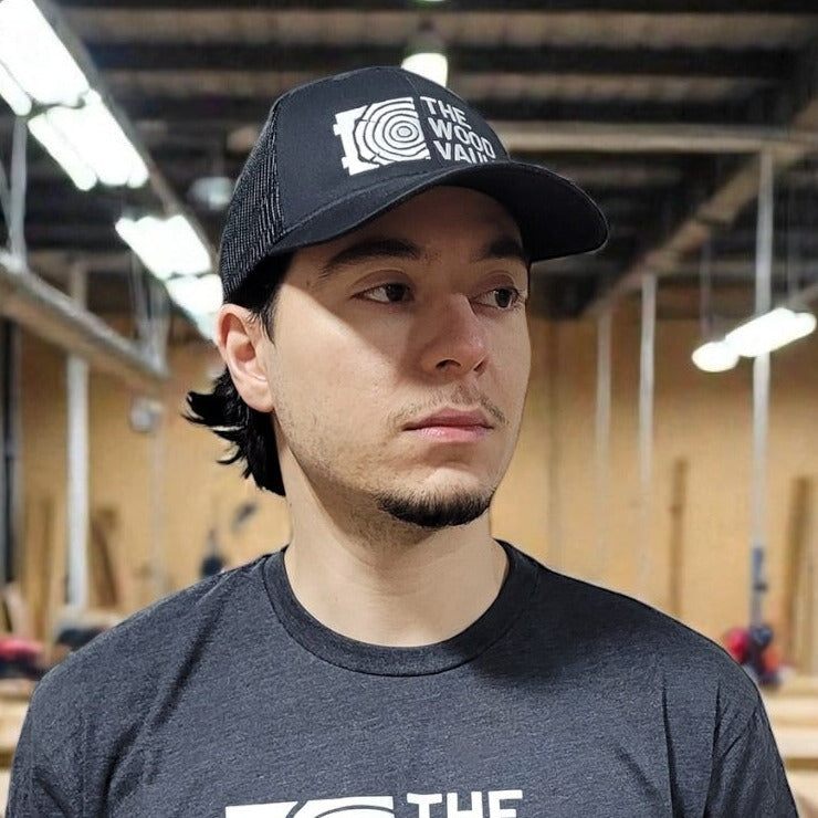 Man wearing a black cap and t-shirt with a logo indoors