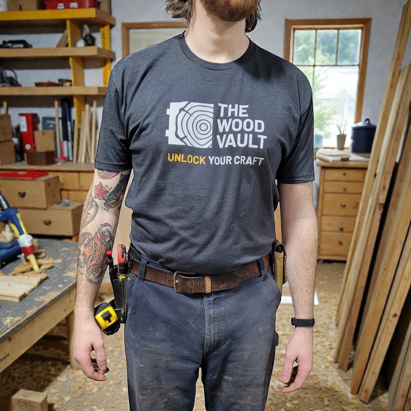 Person wearing a 'The Wood Vault' t-shirt in a workshop setting